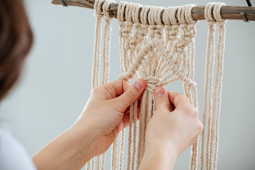 Hands tying a macramé knot